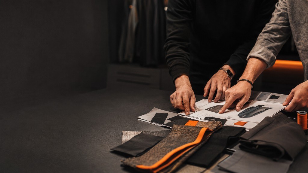 Velnox Wear team reviewing a tech pack, fabric swatches and trims on a studio table